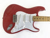 Red electric guitar with white pickguard, three single-coil pickups, maple neck, and chrome hardware on white background
