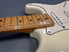 Close-up of vintage white electric guitar body and maple fretboard with single-coil pickups and worn finish
