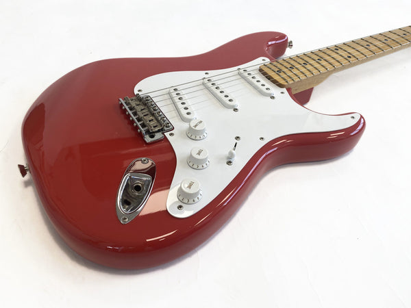 Red electric guitar with white pickguard, three single-coil pickups, volume and tone control knobs, and maple neck on white background