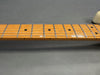 Close-up of maple guitar neck and fretboard with metal frets and dot inlays on a gray background