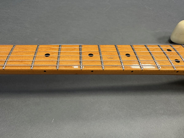 Close-up of maple guitar neck and fretboard with metal frets and dot inlays on a gray background