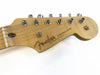 Close-up of natural wood Fender Stratocaster headstock with six tuning pegs and guitar strings on white background