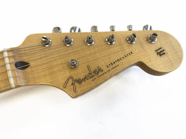 Close-up of natural wood Fender Stratocaster headstock with six tuning pegs and guitar strings on white background