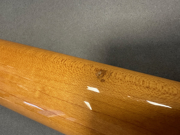 Close-up of glossy finished guitar neck showing detailed wood grain and natural wood knot on dark background