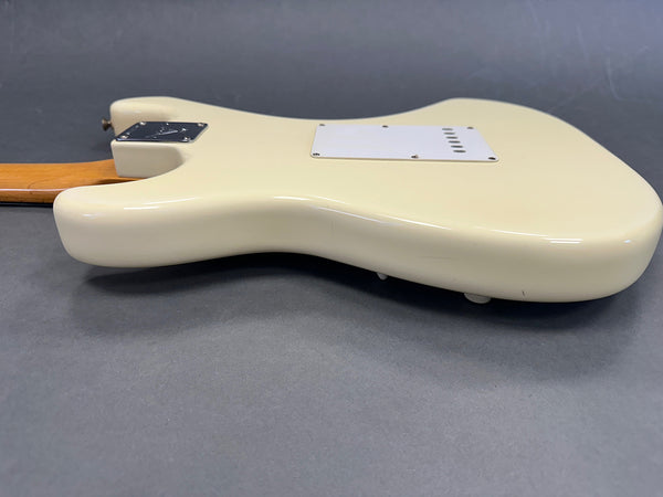 Back view of cream-colored electric guitar body with maple neck on grey background, showing neck plate and rear cavity cover