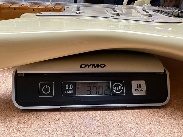 Cream electric guitar body close-up on DYMO digital scale showing weight 3.7 pounds for Coffee House Guitars product listing
