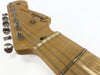 Close-up view of Fender electric guitar headstock with tuning pegs and strings on natural wood finish neck