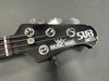 Close-up of Music Man SUB Bass guitar headstock with tuning pegs and worn edges on black finish