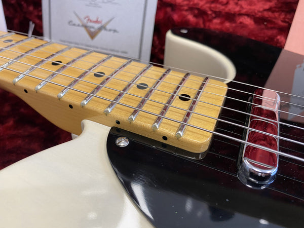 Close-up image of a maple neck and fretboard on a white electric guitar with black pickguard and metal bridge, showcasing guitar strings and frets.