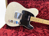 White solid body electric guitar with black pickguard and maple neck in red plush-lined hard case