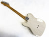 Back view of light-colored solid body electric guitar with maple neck and chrome tuning pegs on white background