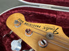 Close-up of Fender Precision Bass headstock with tuning pegs inside plush red guitar case