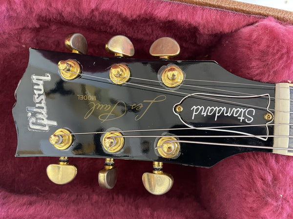 Gibson Standard Les Paul electric guitar headstock with gold tuning pegs on red plush case lining