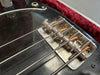 Close-up of metal bridge and strings on black electric bass guitar with red velvet case lining