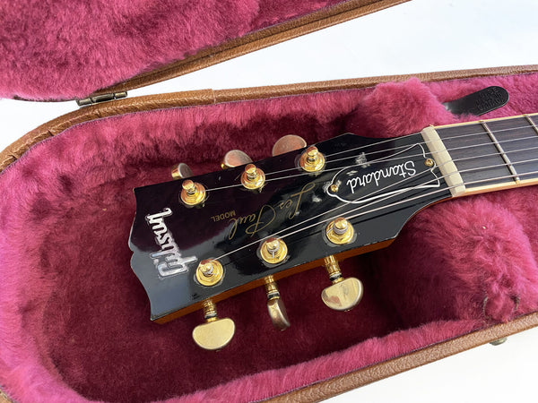 Gibson Les Paul Standard guitar headstock with gold tuning pegs inside pink plush-lined guitar case