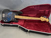 Fender Precision Bass guitar with black body and maple neck in open red velvet-lined Hiscox guitar case on gray background