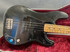 Close-up of black electric bass guitar with maple neck and vintage-style bridge in red velvet-lined guitar case