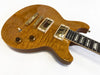 Electric guitar with honey amber quilted maple top, gold hardware, two humbucker pickups, and rosewood fretboard with block inlays on white background