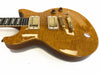Electric guitar with honey-colored quilted maple top, dual humbucker pickups, and gold hardware on white background