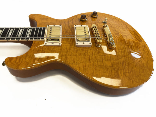 Electric guitar with honey-colored quilted maple top, dual humbucker pickups, and gold hardware on white background