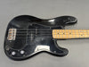 Black electric bass guitar with maple neck, four strings, and chrome hardware on gray background