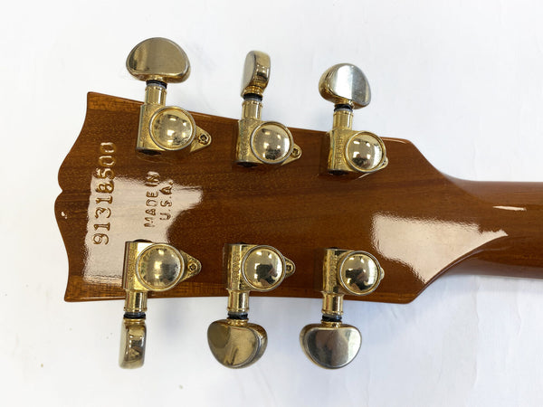 Back of guitar headstock showing serial number 91318500, Made in USA stamp, and six gold Grover tuning pegs on a polished wooden neck