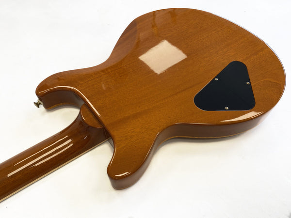 Glossy natural wood finish electric guitar back with black plastic control cavity cover and through-body neck with four visible laminates.