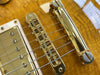 Close-up of gold Tune-o-Matic bridge and tailpiece on honey burst electric guitar with metal humbucker pickup and steel guitar strings