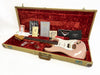 Fender Stratocaster electric guitar in pink with white pickguard inside open vintage tweed case lined with red velvet, accompanied by Fender manuals, certificate of authenticity, tremolo arm, and metal bridge cover