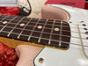 Close-up of electric guitar rosewood fretboard with dot inlays and metal frets, showing white and pink guitar body with strings and pickguard screws, displayed on red plush surface for sale at Coffee House Guitars.