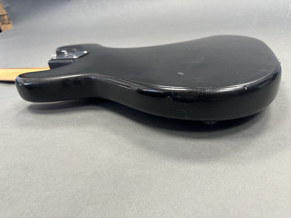 Black electric guitar body with minor scratches and wear, side view on gray background