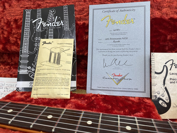 Fender Certificate of Authenticity for 1962 Stratocaster NOS guitar, Fender tremolo springs instruction sheet, owner’s manuals and guitar fretboard on red plush case lining