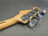 Close-up of natural wood bass guitar headstock with four chrome tuning pegs on gray background