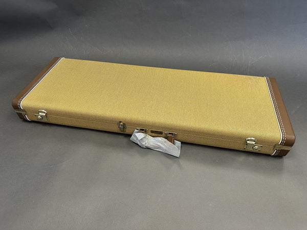 Rectangular tweed guitar case with brown leather corners and metal latches on gray background