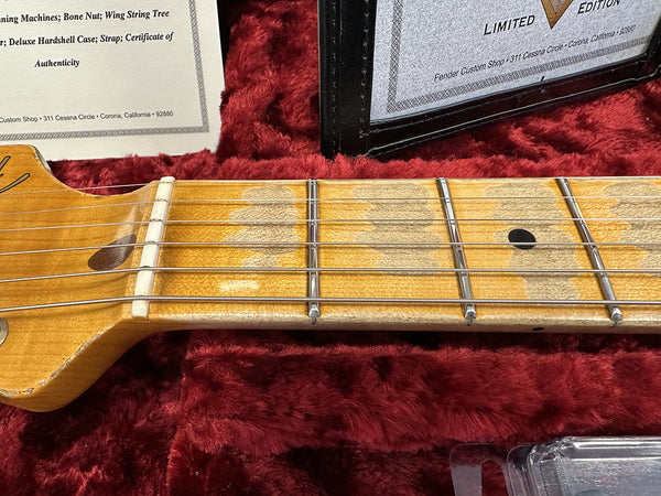 Close-up of vintage maple guitar neck and fretboard with metal frets and dot inlays on red plush guitar case lining with certificate of authenticity from Fender Custom Shop Corona California