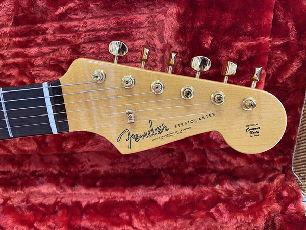 Fender Stratocaster maple guitar headstock with gold tuning pegs on red plush case lining
