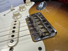 Close-up of vintage electric guitar bridge, pickup, and tone volume knobs on sunburst finish guitar body