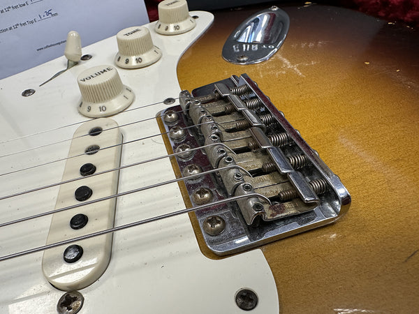 Close-up of vintage electric guitar bridge, pickup, and tone volume knobs on sunburst finish guitar body