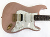Rose pink electric guitar with white pickguard, gold hardware, and dark wood fretboard on white background