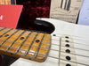 Close-up of a vintage electric guitar maple fretboard with worn frets and white single-coil pickups, showcasing strings and part of the guitar body with manuals in the background