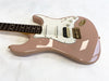 Electric guitar in dusty pink finish with white pickguard, three pickups including a humbucker, and rosewood fretboard on plain white background