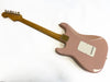 Back view of pink electric guitar with maple neck and six tuning pegs against white background