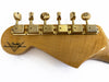 Back view of Fender Custom Shop guitar headstock with gold tuning pegs on natural wood finish