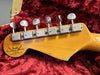 Close-up of vintage Fender Custom Shop Limited Edition electric guitar headstock with six vintage tuning pegs on red plush interior guitar case lining