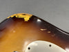 Close-up of vintage sunburst electric guitar body showing worn and chipped paint near white pickguard.