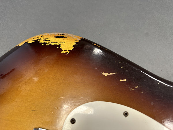 Close-up of vintage sunburst electric guitar body showing worn and chipped paint near white pickguard.