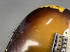 Close-up of relic sunburst electric guitar body with worn paint and vintage Fender bridge showing aging and wear details