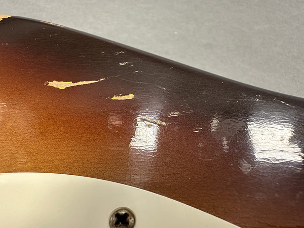 Close-up of guitar body with worn sunburst finish and visible paint chips near pickup screw on electric guitar