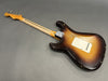 Vintage sunburst electric guitar with worn finish and maple neck shown from back on gray surface