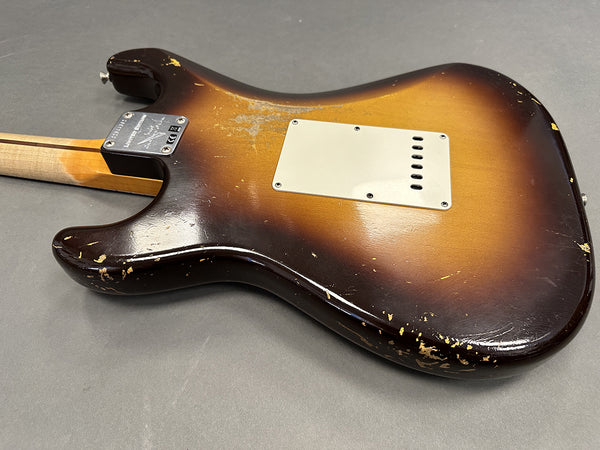 Back of sunburst electric guitar body showing aged finish and rear plastic cover plate on gray background